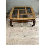 A walnut coffee table of oriental design, the surface inset with bevelled glass panels and with