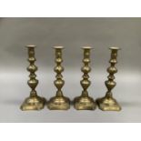 A set of four Victorian brass candlesticks with baluster columns on a domed and square canted