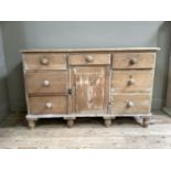 A Victorian pine dresser having a drawer and single door to the centre flanked by three graduated
