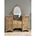 A pine dressing table having an oval mirror above a sunken centre with two drawers flanked by a