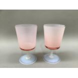 A pair of pink tinted and opalescent glass goblets with bucket bowls and slender stem on a