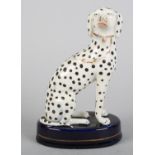 A MID 19TH CENTURY STAFFORDSHIRE POTTERY DALMATIAN, seated on a dark blue oval base with gilt rim