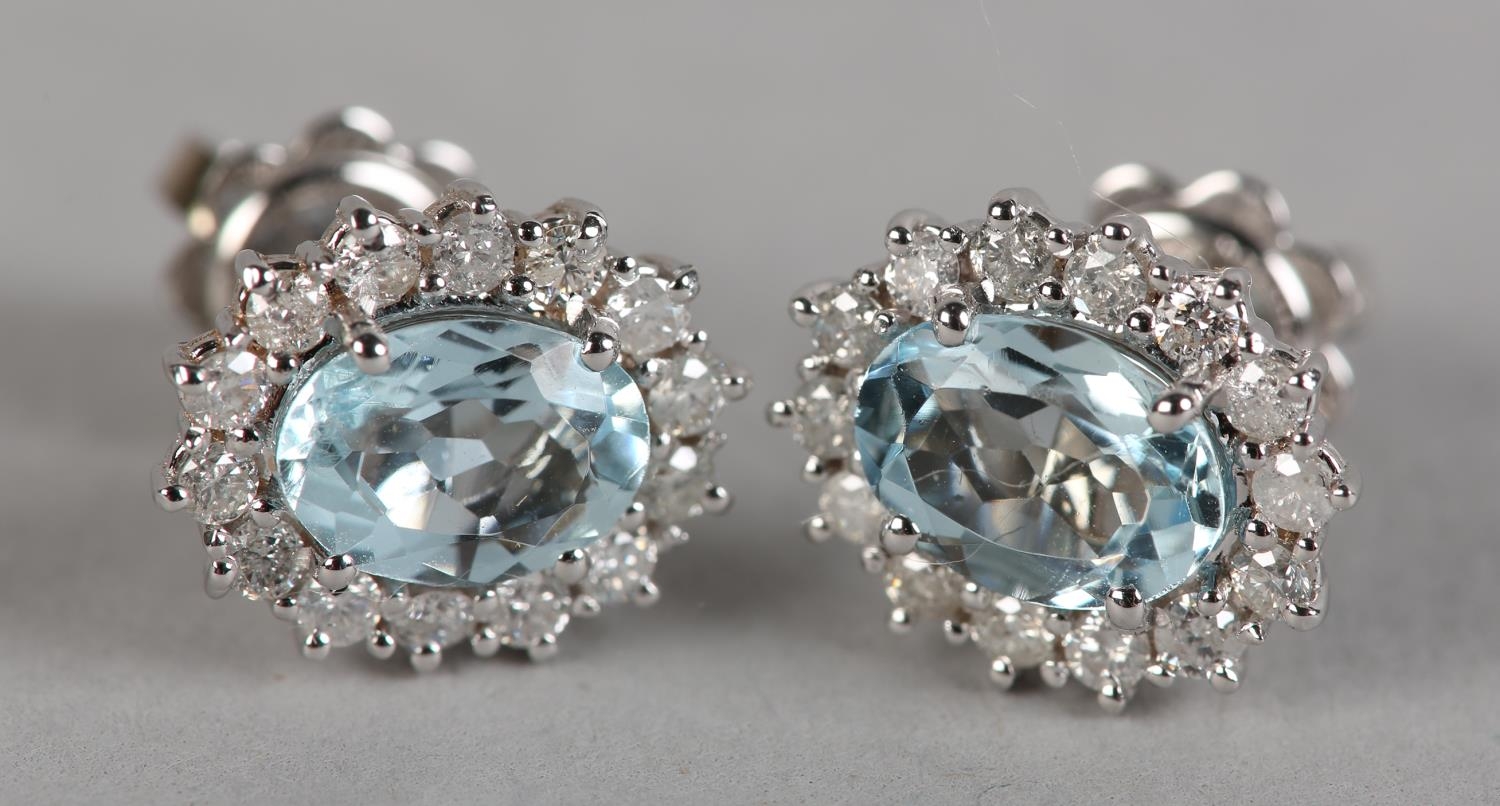 A PAIR OF AQUAMARINE AND DIAMOND CLUSTER EAR STUDS, each claw set to the centre with an oval faceted