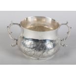 A 17TH CENTURY SILVER PORRINGER, London 1667, chased with tulips on a stipple ground to the lower