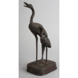 A JAPANESE BRONZE GROUP OF CRANE AND YOUNG, raised on a rounded rectangular plinth, Meiji period,
