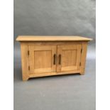 A small pale oak cabinet of two doors on stile feet, 95cm wide