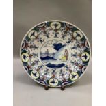 A 19th century tin glazed charger painted in underglaze blue, yellow and iron red in the chinoiserie