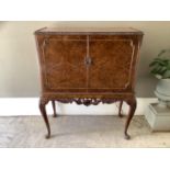 A figured walnut drinks cabinet with mirror backed interior, shelves and drawer, on cabriole legs