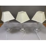 A set of three perspex table lights of square form complete with cream shades, overall height 50cm