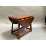 An oak oval drop leaf occasional gate leg table on square and turned framing