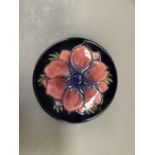 A Moorcroft pin dish painted and tube lined with anemone against a dark blue ground, impressed