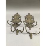 A pair of Victorian brass candle wall brackets of shield shape, cast with dolphins, rocaille and