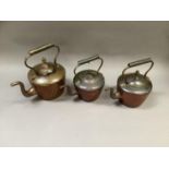 Three copper kettles of circular outline, 33cm over the handle, 28cm over the handle and 27cm over