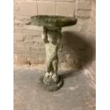 A garden bird bath, cast concrete, in the form of a cherub holding aloft a bowl, 76cm high by 44cm