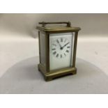 A brass carriage clock the white dial having black Roman numerals engraved with presentation