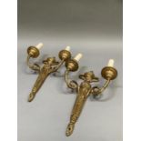 A pair of gilt metal twin light wall sconces of classical design, two handled urn finial and leaf