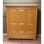 A Barker and Stonehouse pale beech wardrobe having a moulded cornice above three panel doors with