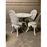 A white metal patio table and four matching chairs of pierced design