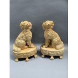 A pair of reproduction Staffordshire style spaniels, seated on an oval base, bordered with stiff