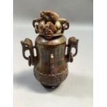 A Chinese carved soapstone vase and cover, the cover carved in high relief with a mythical beast,