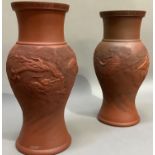 A pair of Chinese red clay vases, the baluster bodies moulded with sinuous dragons, seal marks to