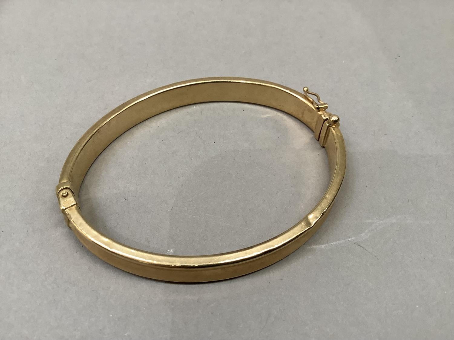 A stiff hinged bangle, concave hollow tube in yellow metal (tests as 9ct gold), approximate weight