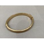 A stiff hinged bangle, concave hollow tube in yellow metal (tests as 9ct gold), approximate weight