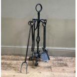 A set of four wrought iron fire irons on a four arm stand to include shovel, poker, brush and