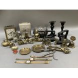 A carriage clock and a white metal clock, a pair of metal candlesticks, two flat irons and various