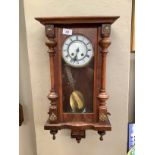 A Victorian walnut wall clock having a white enamel two part dial with Roman numerals and 8 day