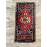 A small prayer rug, the black field with red medallion and further camel coloured medallion