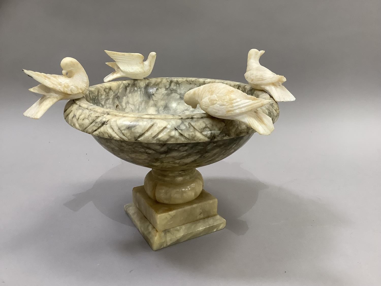 A pedestal bowl with Pliny doves perched on the rim, alabaster, approximately 31cm diameter by