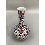 A bottle shaped vase painted with all over scrolling leafage in underglaze blue, iron red and