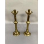 A pair of brass candlesticks with castellated drip trays, octagonal knopped column and domed base,