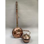 A copper and brass warming pan on a turned fruit wood handle together with a copper kettle.