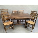 An oak draw leaf dining table on refectory supports and six ladder back rush seated dining chairs,