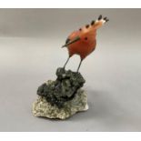 A Brazilian mineral specimen carving of a crested bird with fanned tail feathers, perched on a rock,