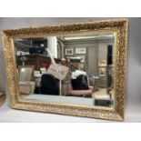 Gilt framed rectangular wall mirror, bevelled glass, flower mould into frame, 76cm x 107cm