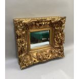 A rectangular gilt framed wall mirror with bevelled glass and deeply moulded floral frame, 52cm wide