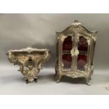 An EPNS glazed vitrine and wall bracket of roccoco design, lined in red velvet with glass shelf,
