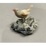 A Brazilian mineral specimen carving of a finch or songbird perched on a rock, 9.5cm high