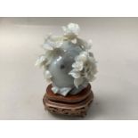 A Chinese mineral carving of songbirds perched upon a peach and blossom, 11cm high, with stand and