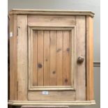 A small pine hanging corner cupboard with single door