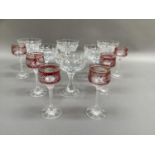 A set of six cut glass Champagne coupes together with six ruby stemmed liqueur glasses