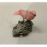 A Brazilian carved mineral specimen of a songbird perched on a rock, 9cm high