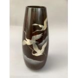 A Japanese bronze effect and white metal inlaid vase, inlaid with cranes in flight above clouds,