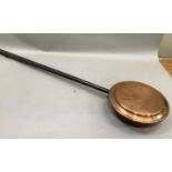 A copper warming pan on iron handle