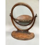 A walnut toilet mirror of oval outline on a half moon base, 63cm overall width, 80cm high