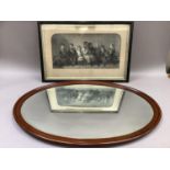 A mahogany framed bevelled wall mirror of oval outline measuring 57cm x 82cm together with a black