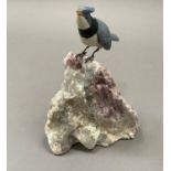 A Brazilian carved finch on a rock in mineral specimens, 16.5cm high